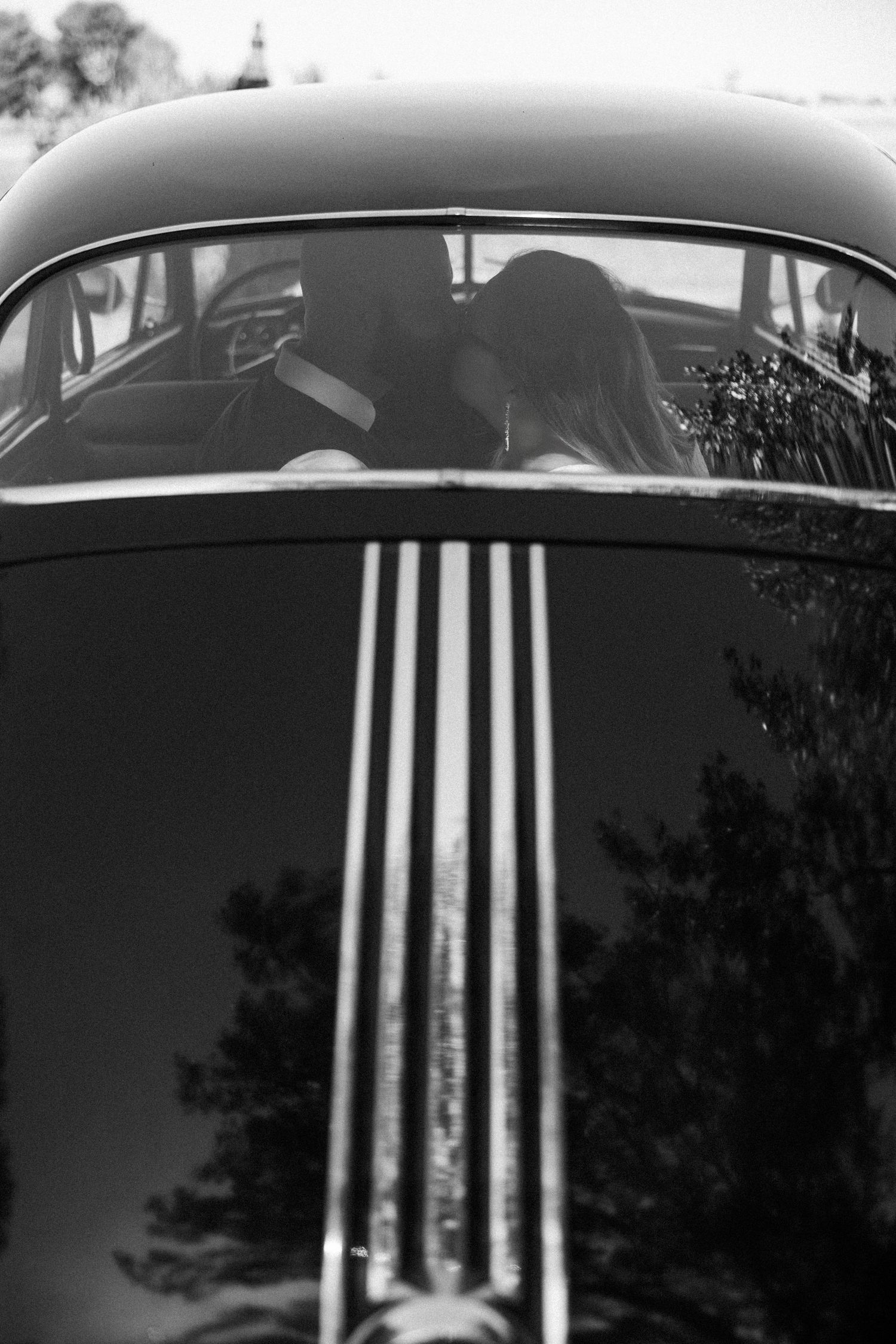 Black and white detail shots of a vintage car's chrome grille and hood ornament.