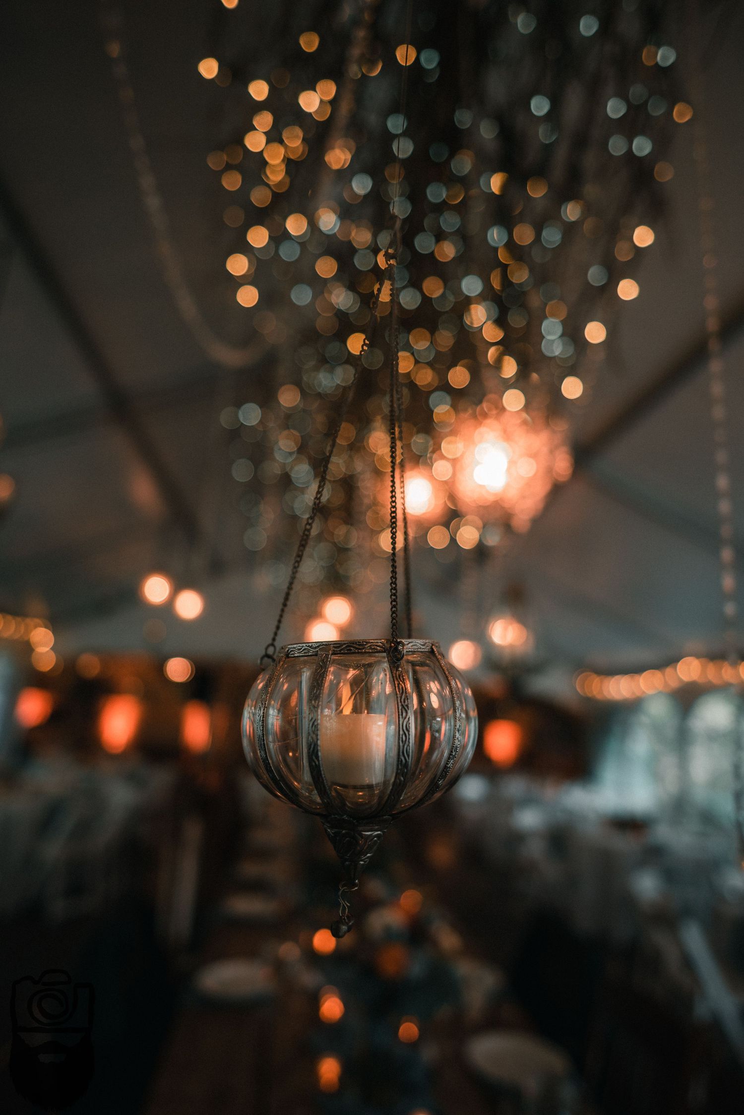 Crystal chandelier and hanging lights create a magical bokeh effect in an evening event space.