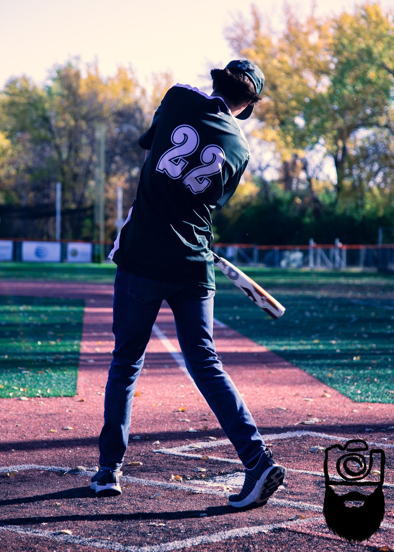 Baseball player in black uniform practicing pitching motions on a field during fall season.