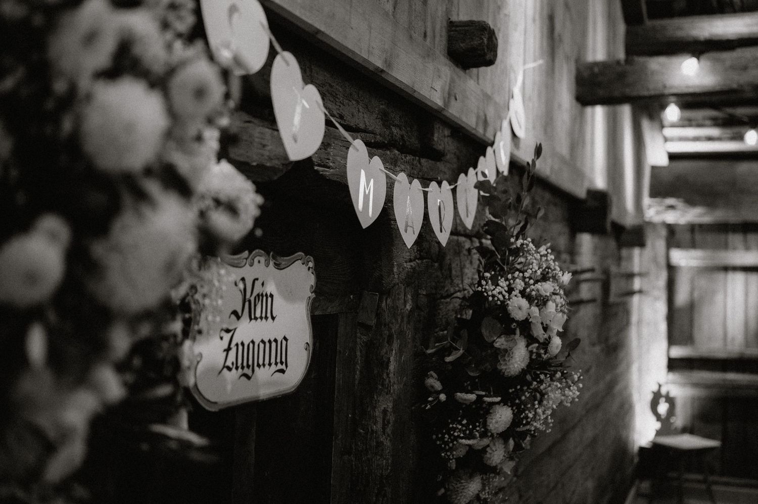 Romantic black and white detail shot of wedding decorations with heart-shaped signs in a barn setting.