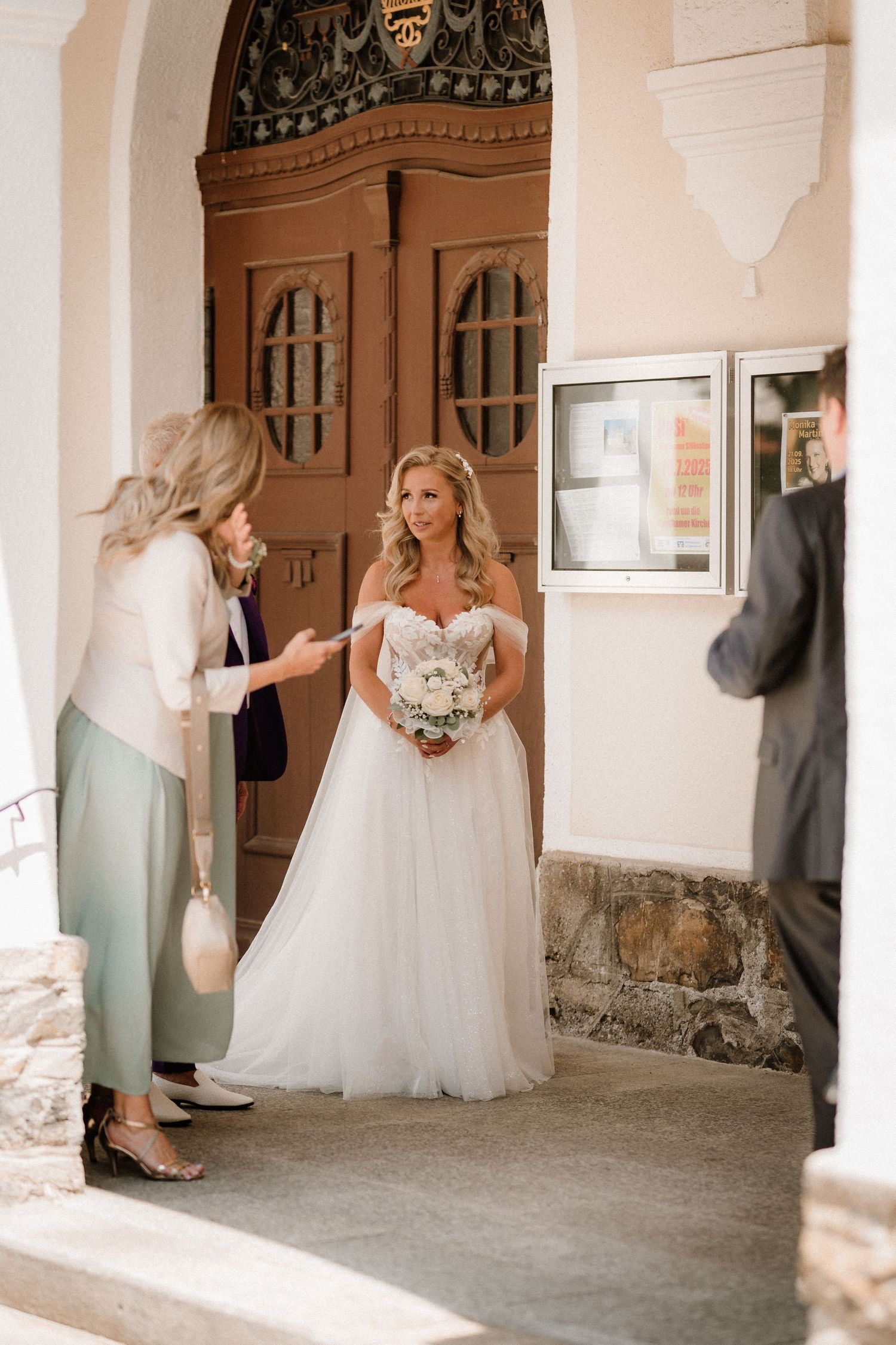 Wedding party gathering in an elegant church hallway with ornate wooden details.