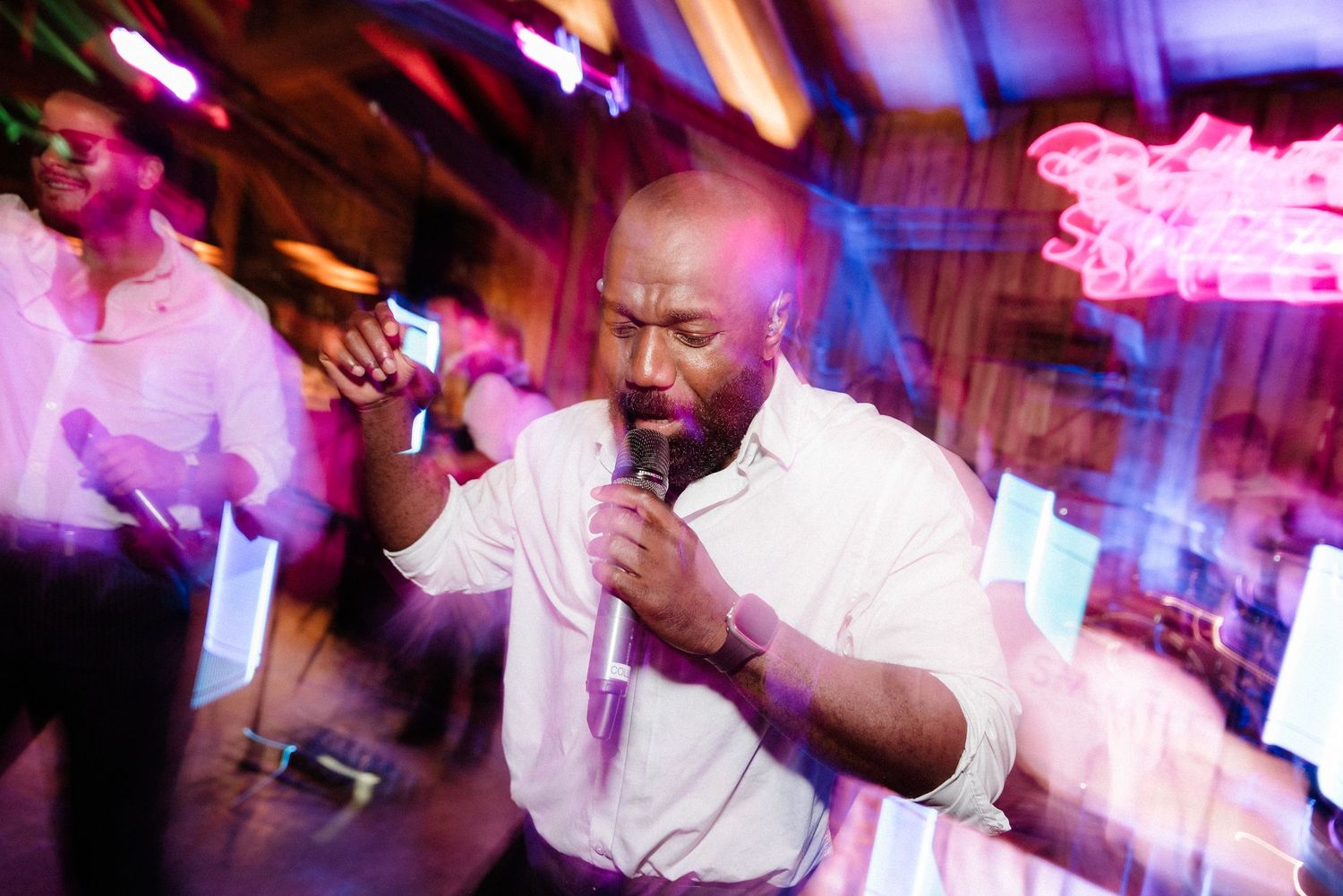 Dance party at wedding reception with colorful neon lighting and motion blur effects.