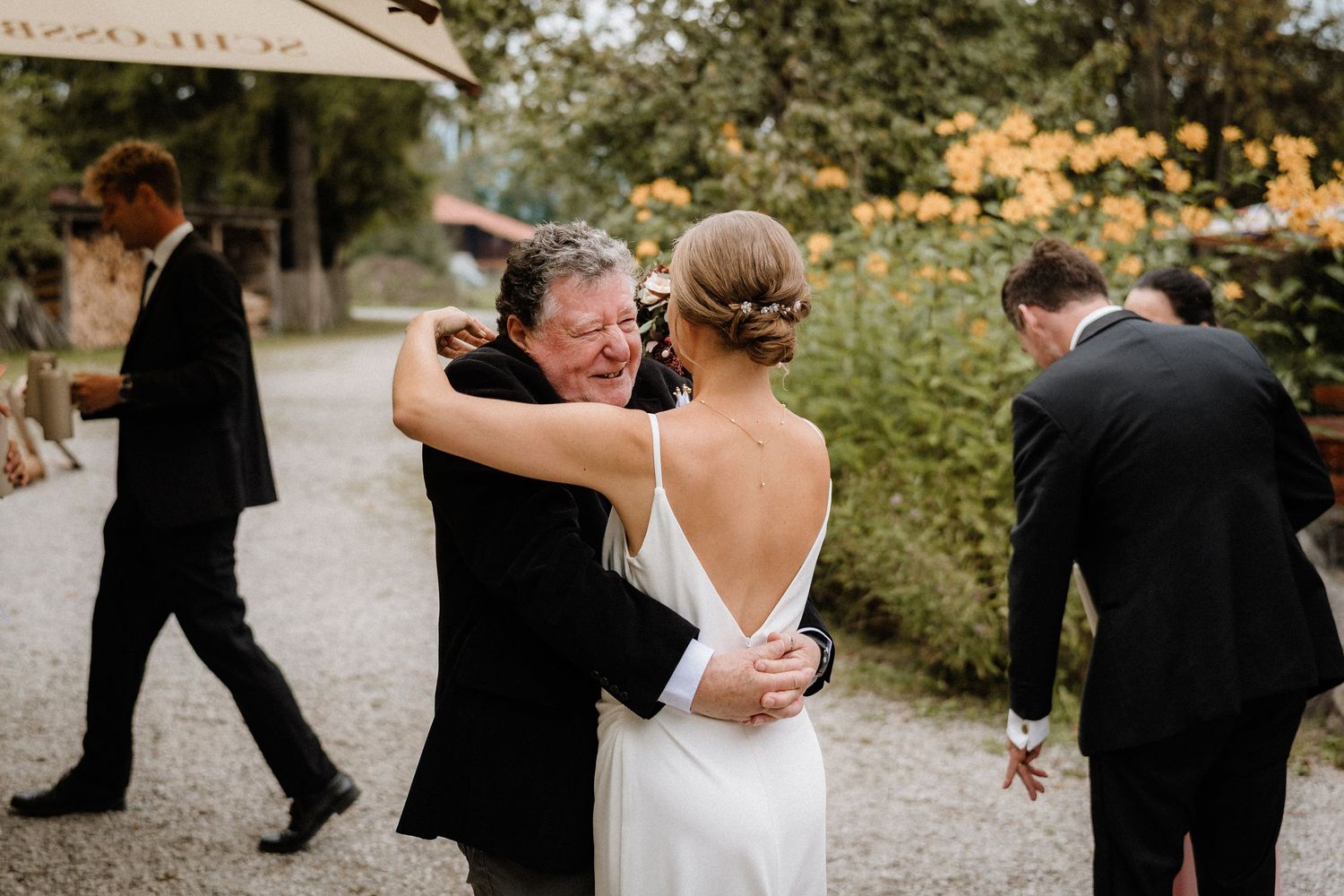 Emotional embrace captured during outdoor wedding reception on gravel path.