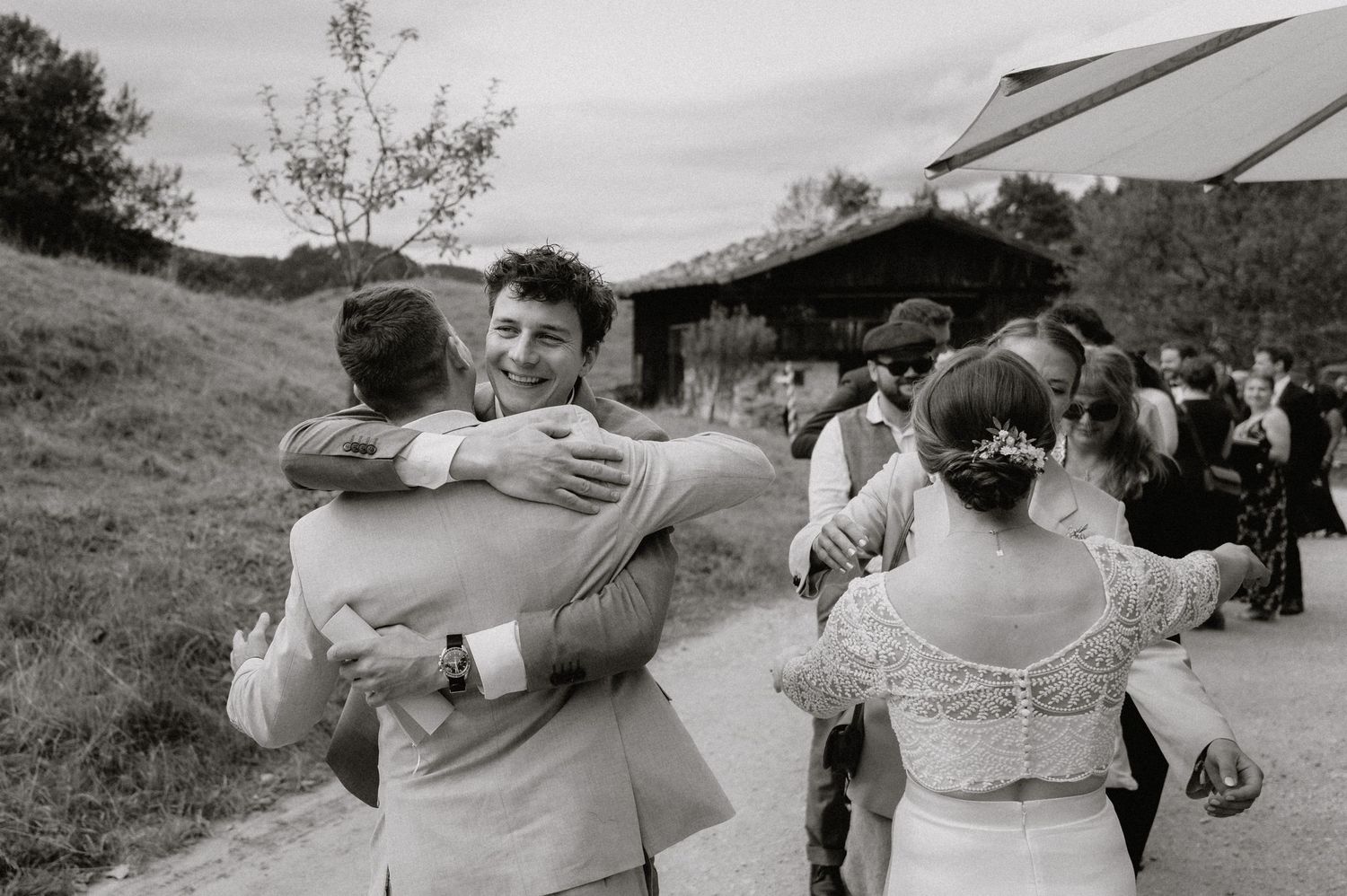 Black and white photo of wedding guests dancing and celebrating outdoors.