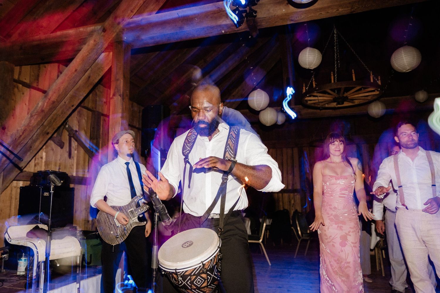 Wedding band performing live music in a rustic barn venue with decorative lighting.