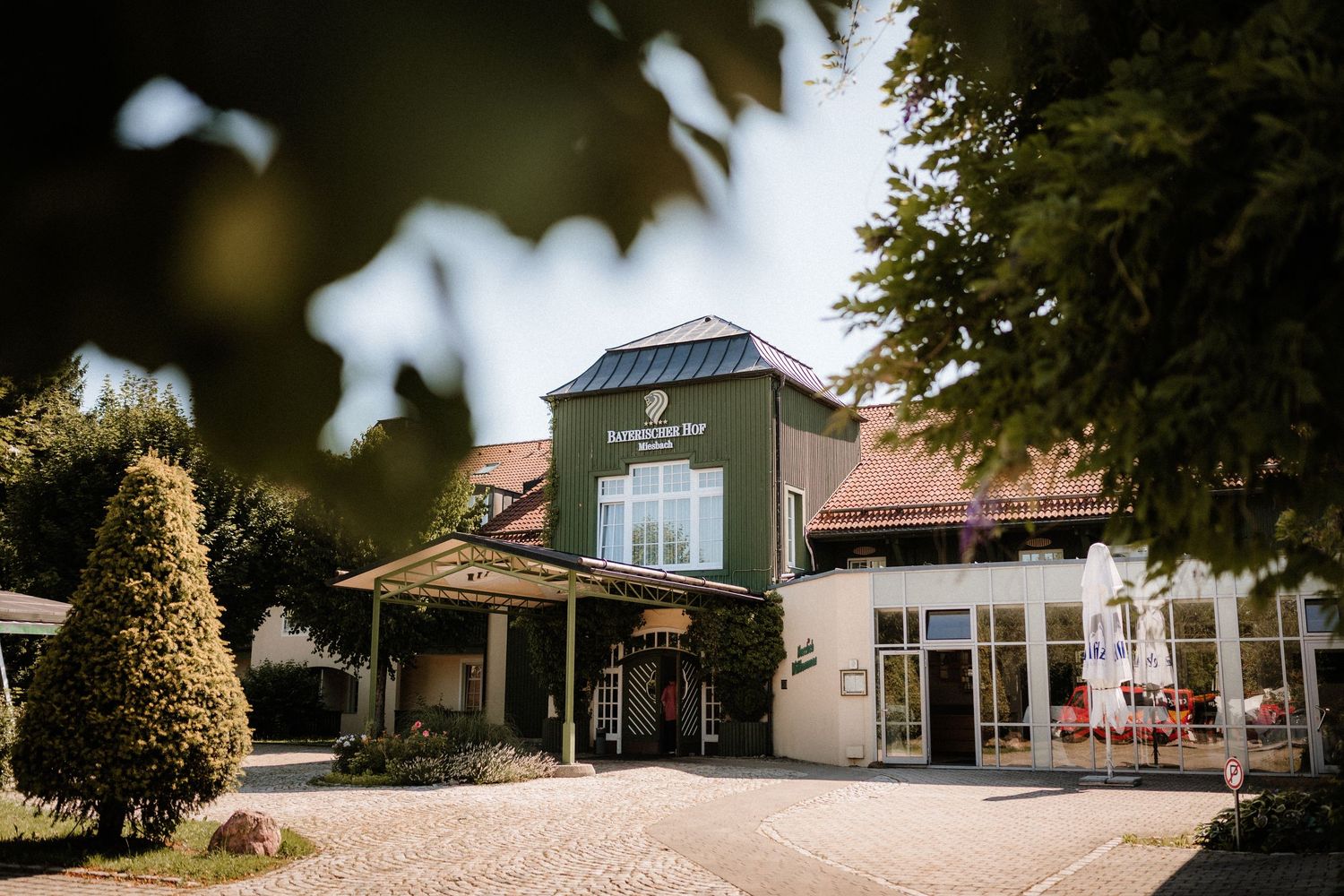 Panoramic view of a rustic wedding venue exterior with trees and buildings.