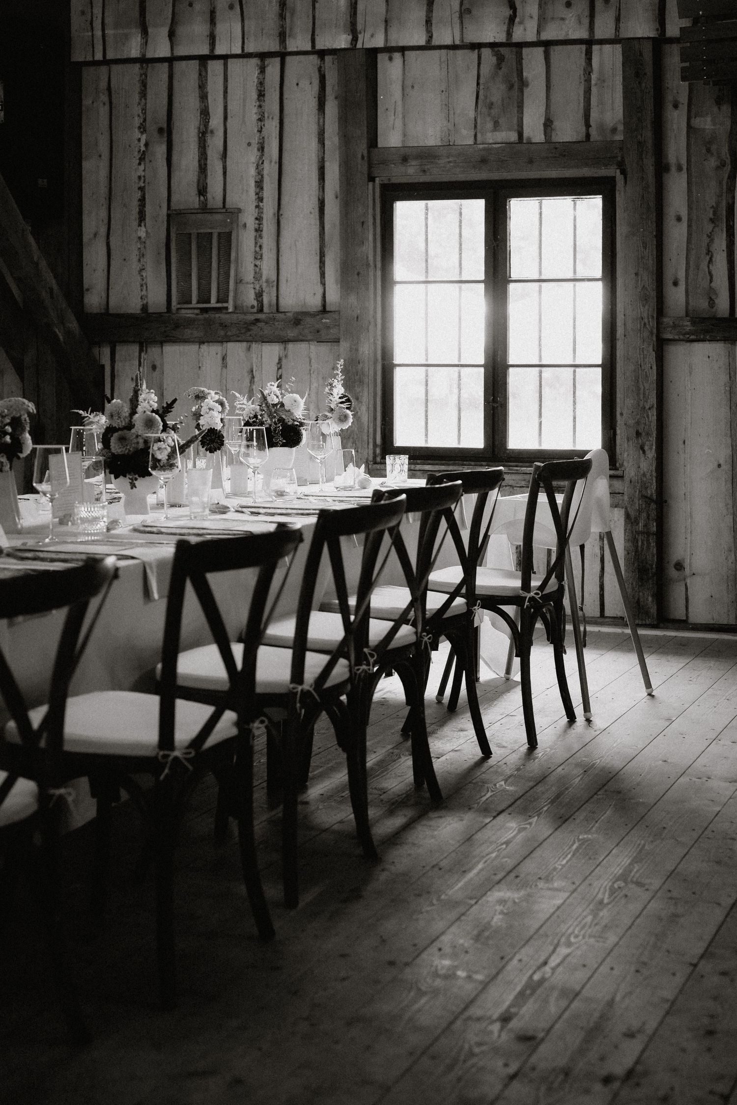 Rustic barn wedding reception setup with wooden tables and chairs in natural light.