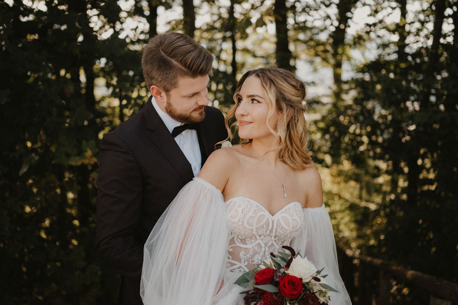 A romantic sunset wedding portrait with golden light filtering through trees.