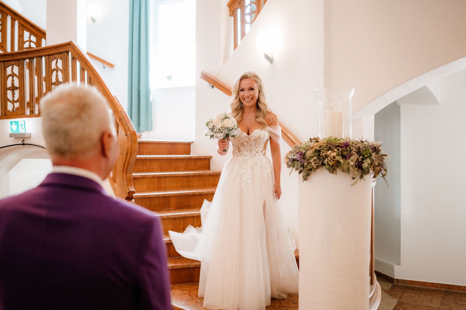 Emotional first look moment on wooden staircase during wedding day.