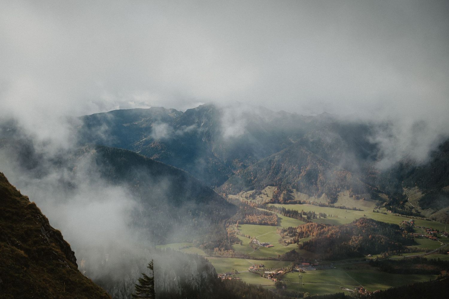 Panoramic mountain landscape with fog rolling over green valleys and peaks.