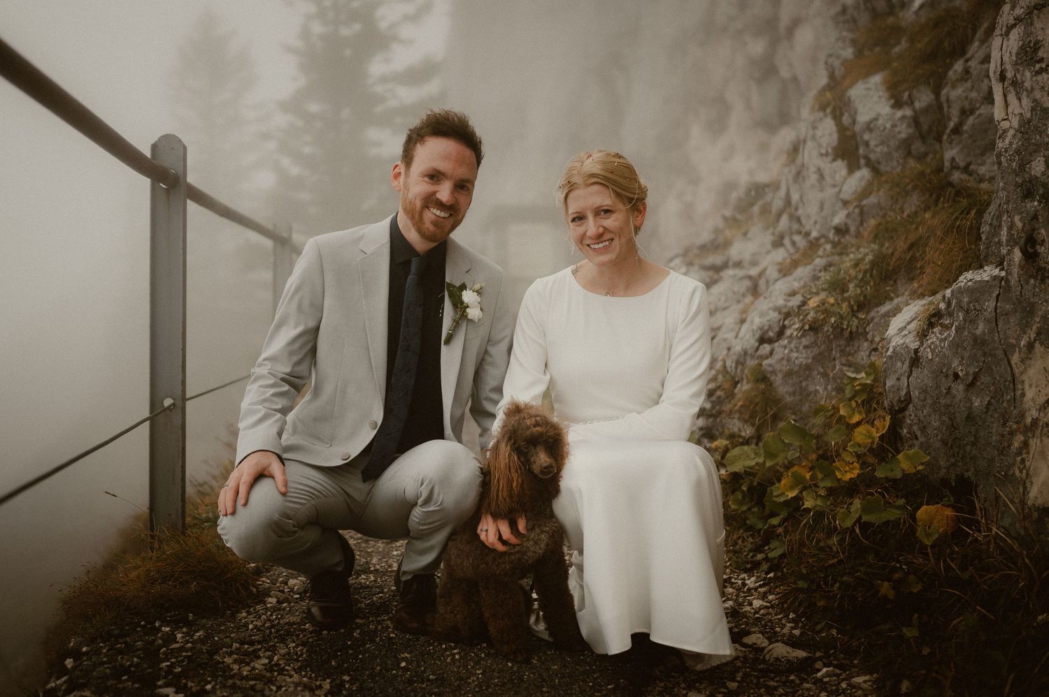 A couple shares joyful moments together on a misty mountain trail.
