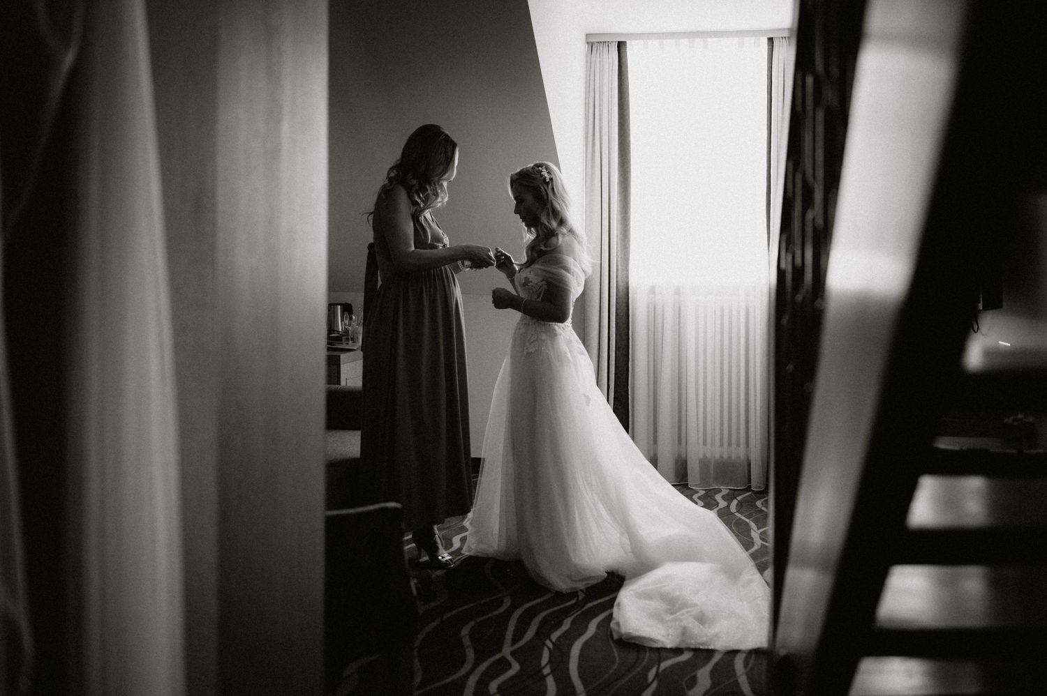 Silhouetted figures prepare in a room with dramatic window lighting.