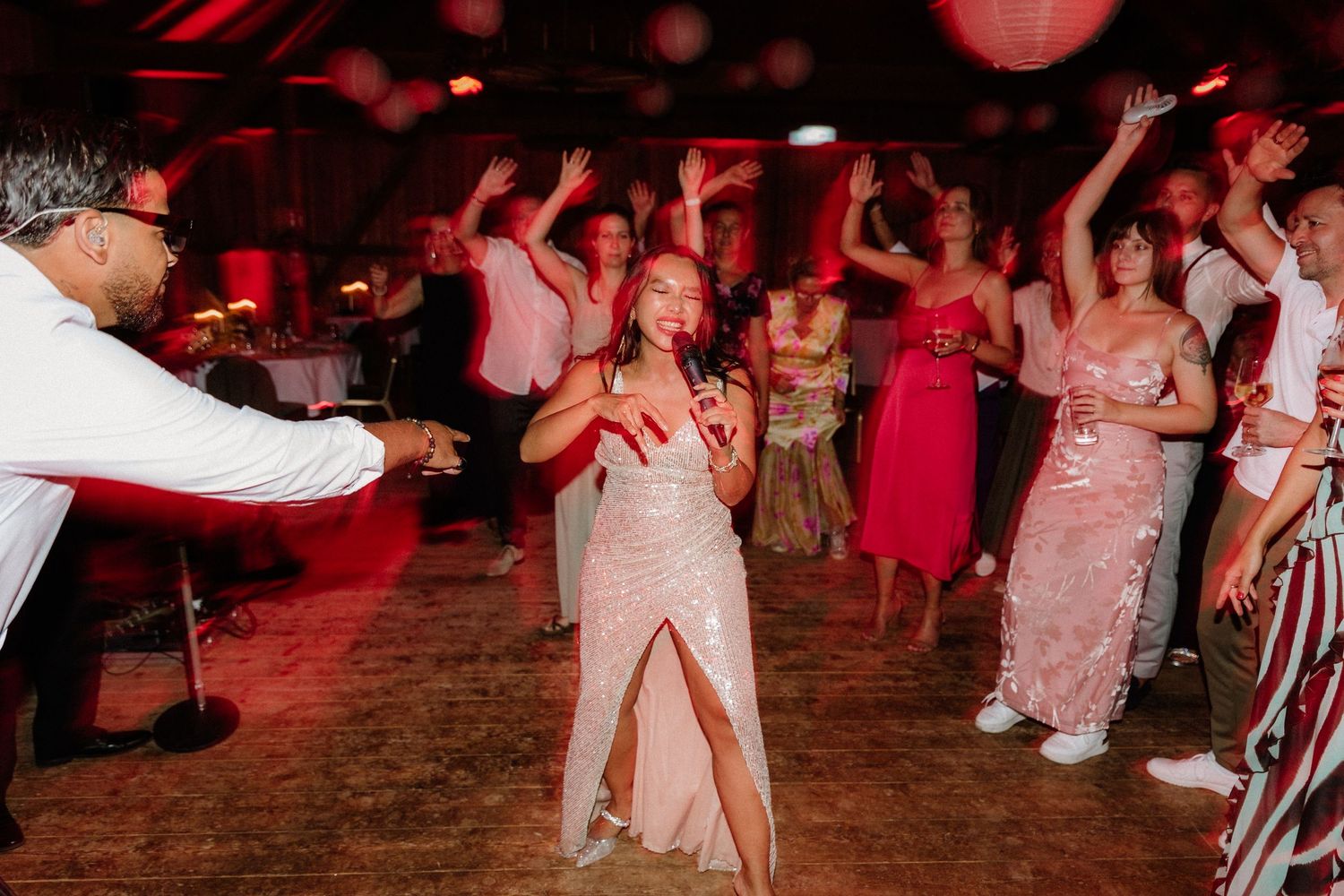 Energetic dance party scene with guests celebrating under red mood lighting.