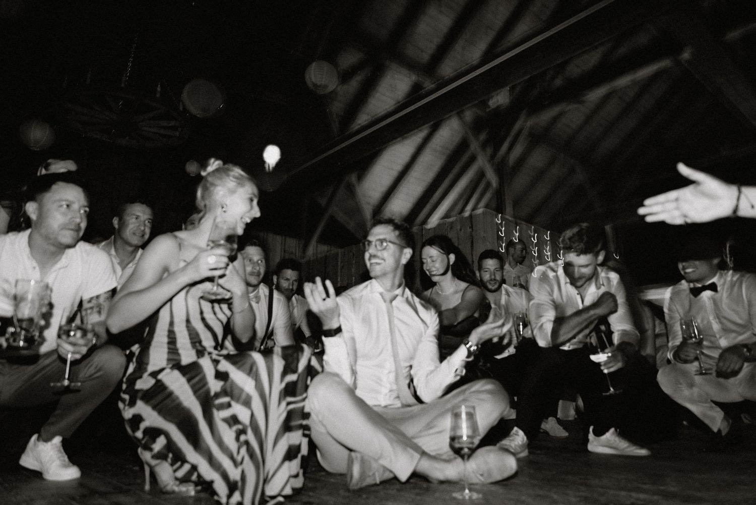 Black and white shot of guests dancing at a dimly lit indoor party venue.