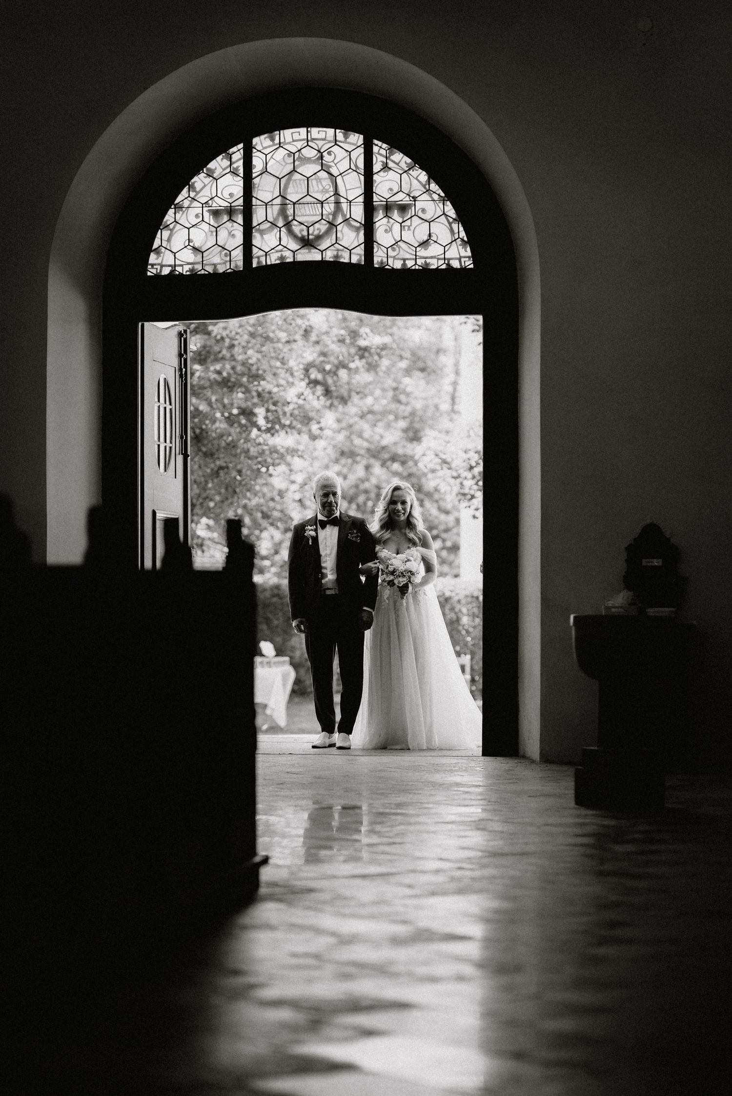 Dramatic black and white sequence of wedding processional through arched church doorway.