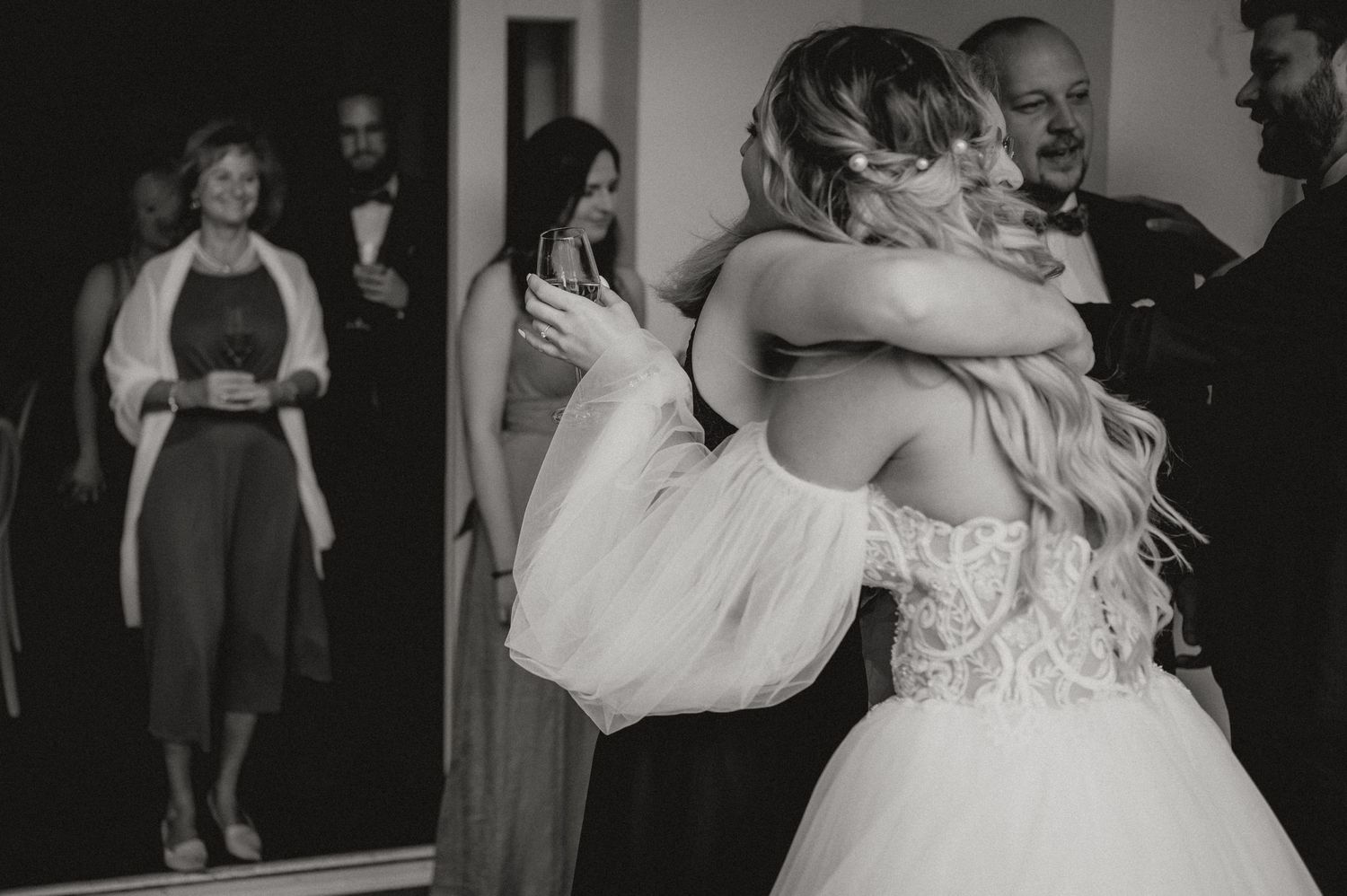 Wedding reception guests embracing and celebrating in formal attire.