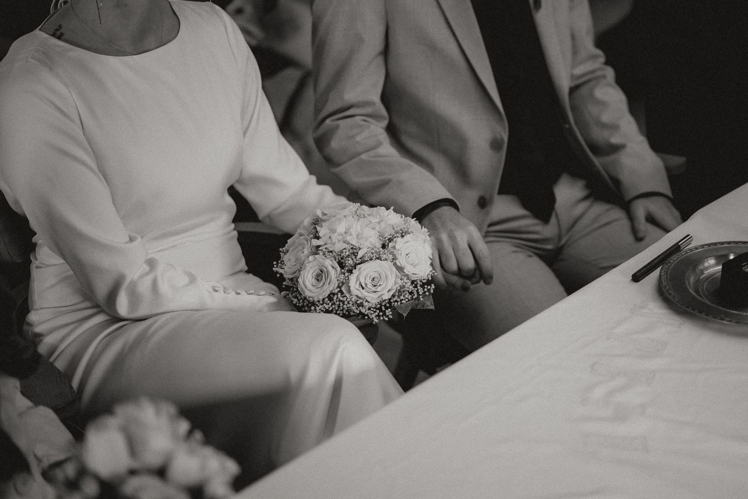 Black and white photo of wedding guests seated at tables during an indoor reception.