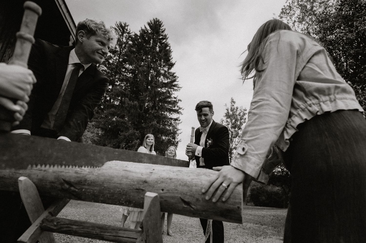 Black and white photo of people participating in a traditional log sawing ceremony.