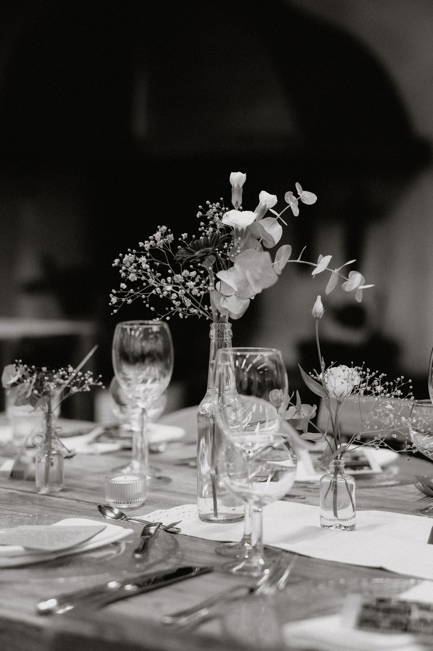 Elegant table settings with delicate flowers in glass vases for a wedding reception.