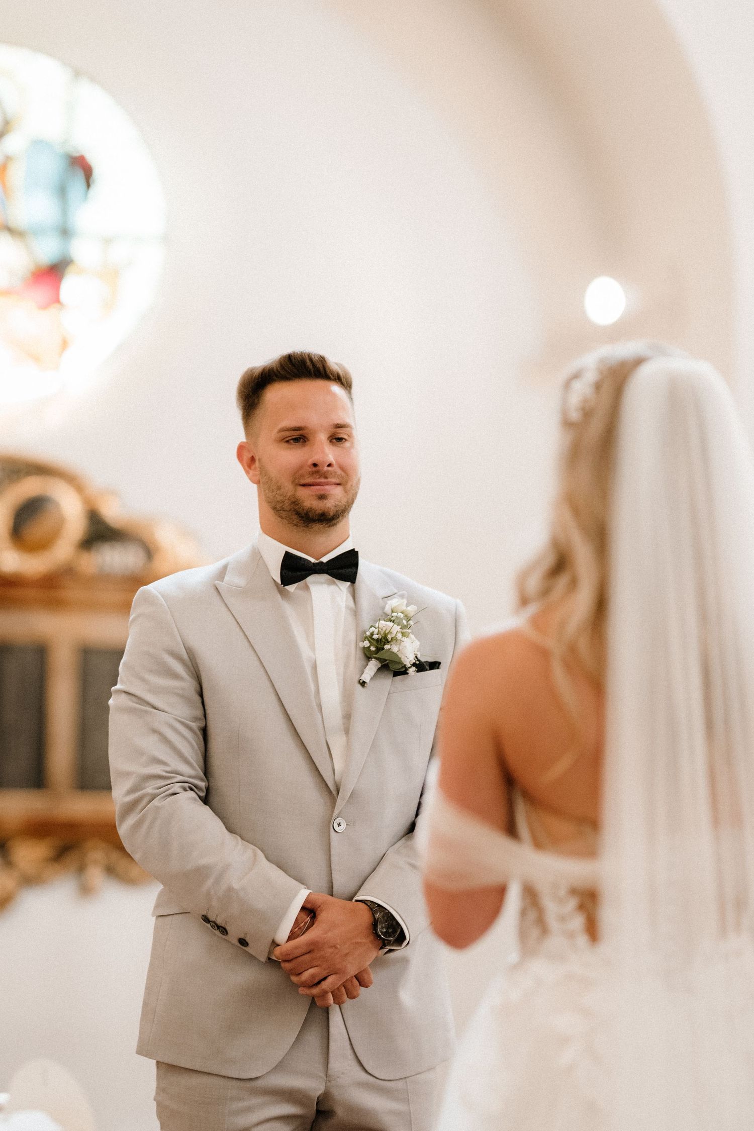 A first look moment between newlyweds in a church with soft lighting and arched architecture.