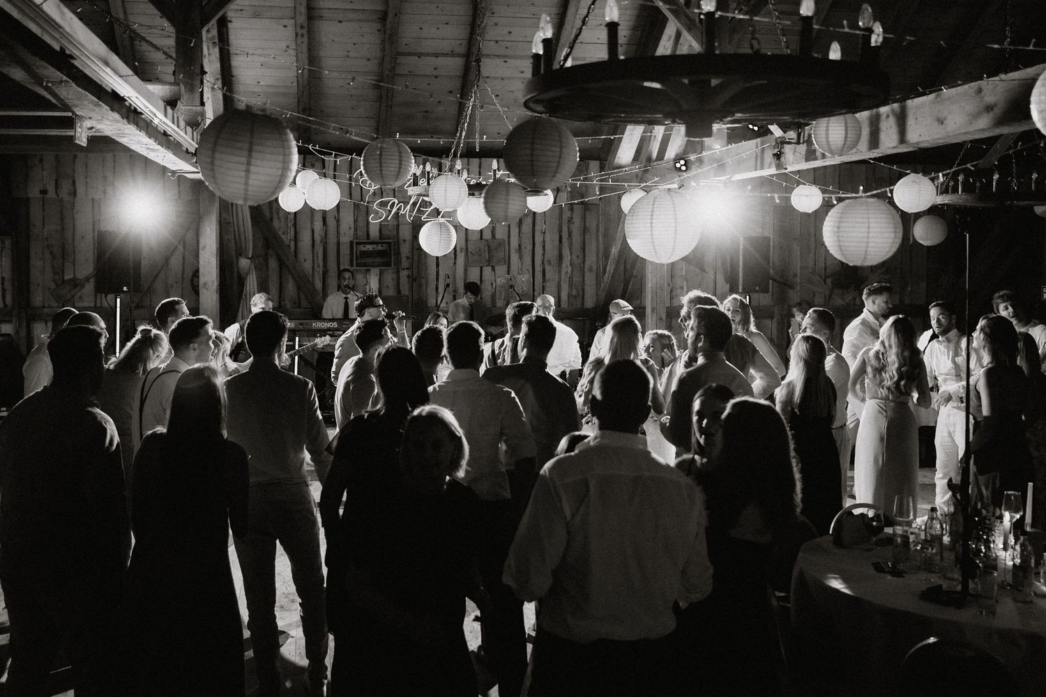 Wedding reception guests dancing and celebrating under paper lanterns with dynamic lighting effects.