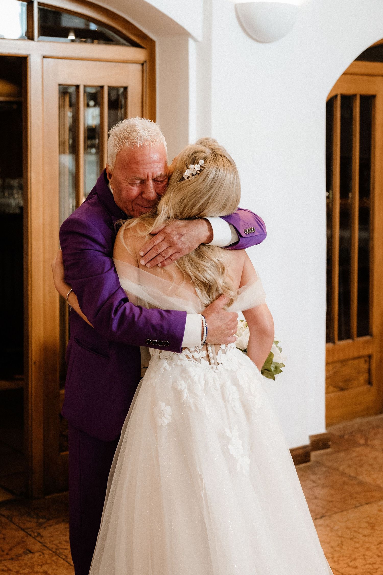 Emotional wedding moment captured in a series showing an embrace in white dress and purple attire.