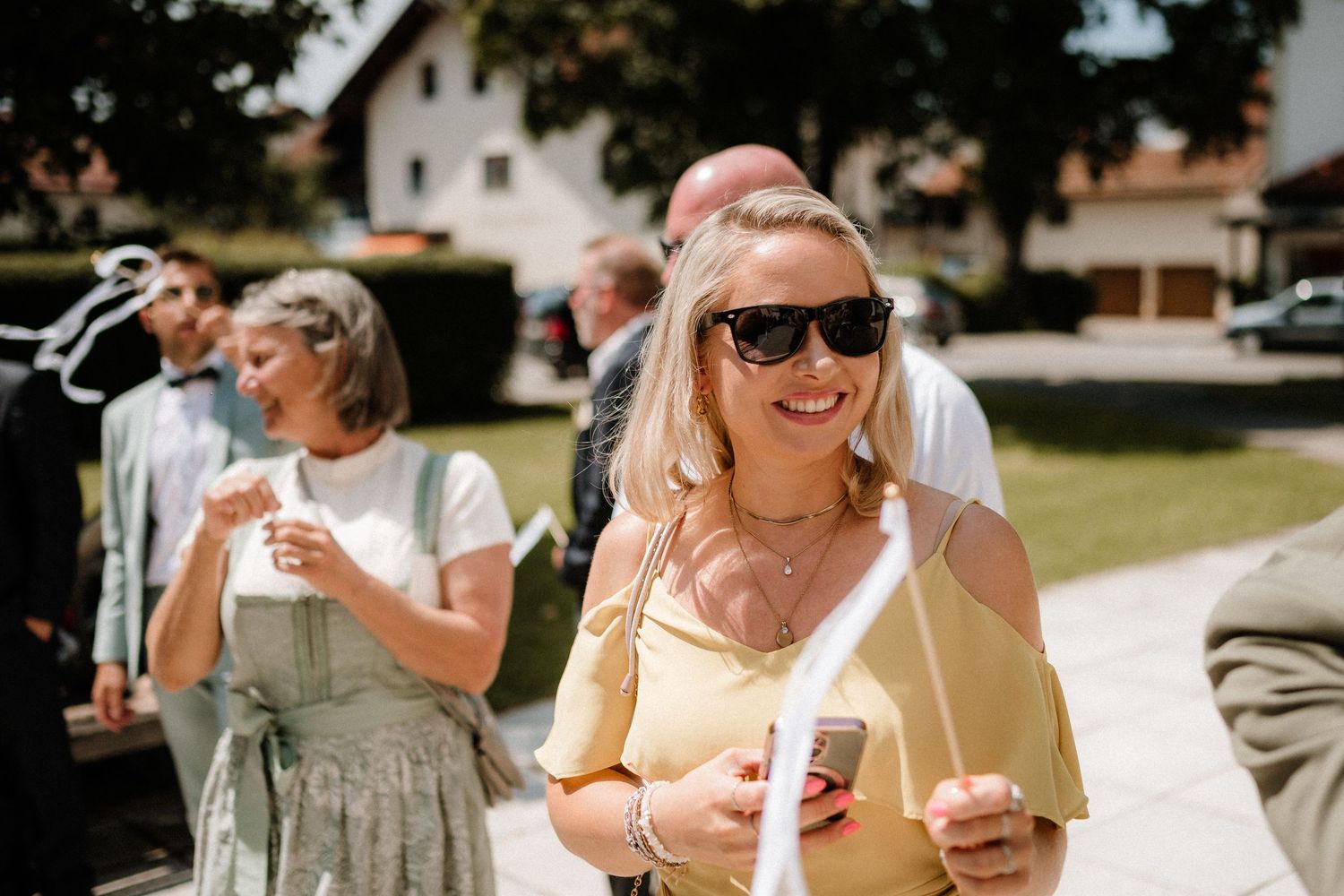 Guests enjoy drinks and laughter during an outdoor summer wedding celebration.