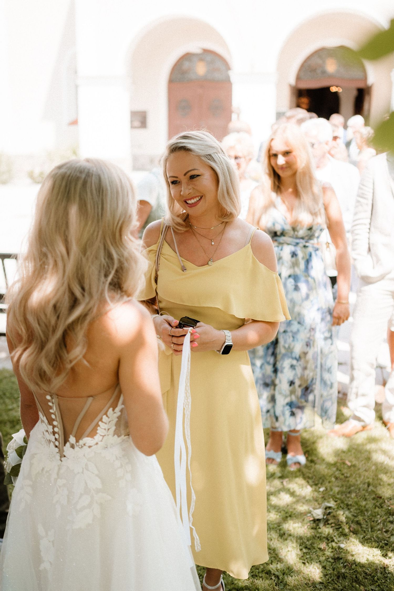 Wedding celebration moments captured in bright sunlight under white arches.