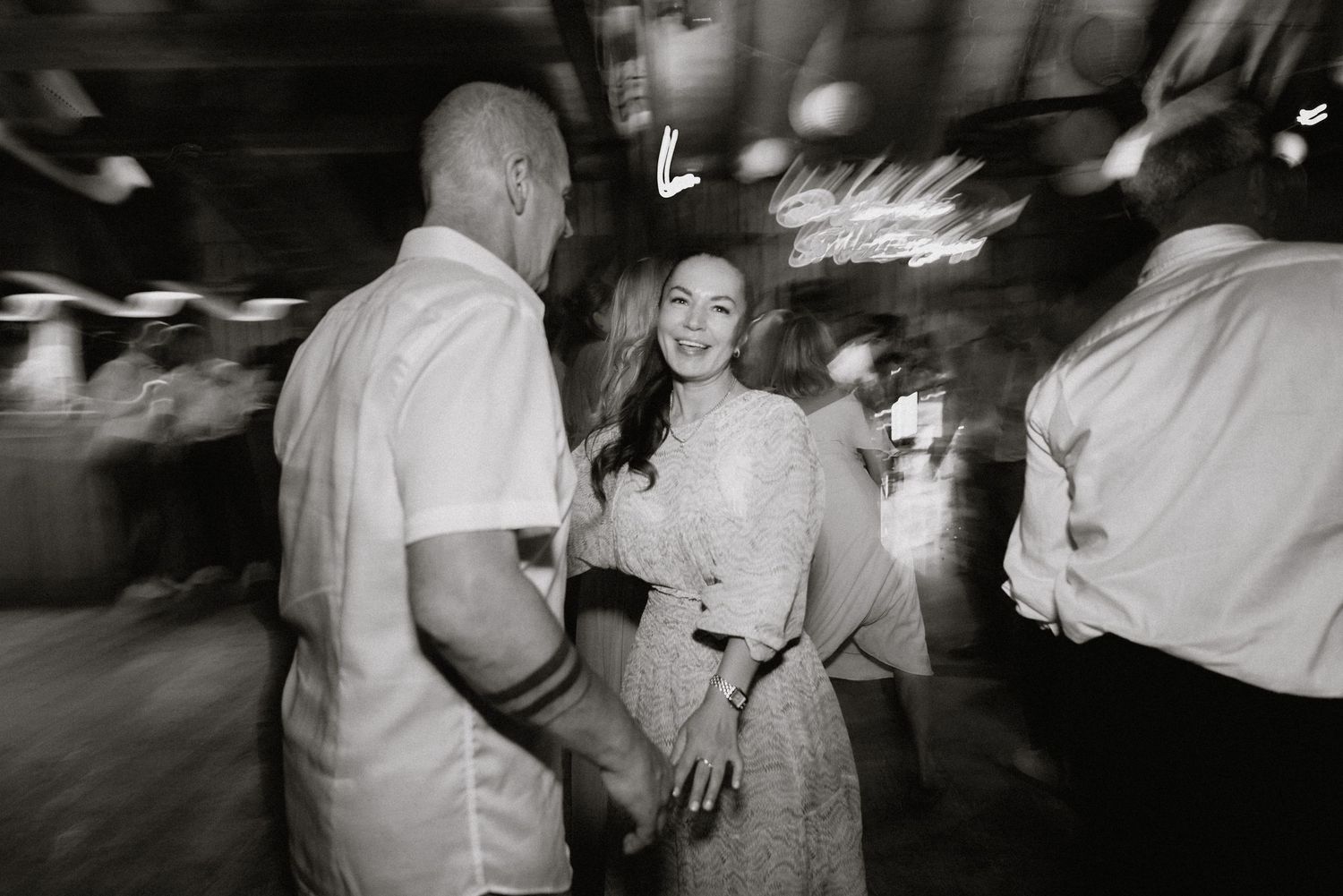 Black and white candid shots of wedding guests dancing at a lively reception.