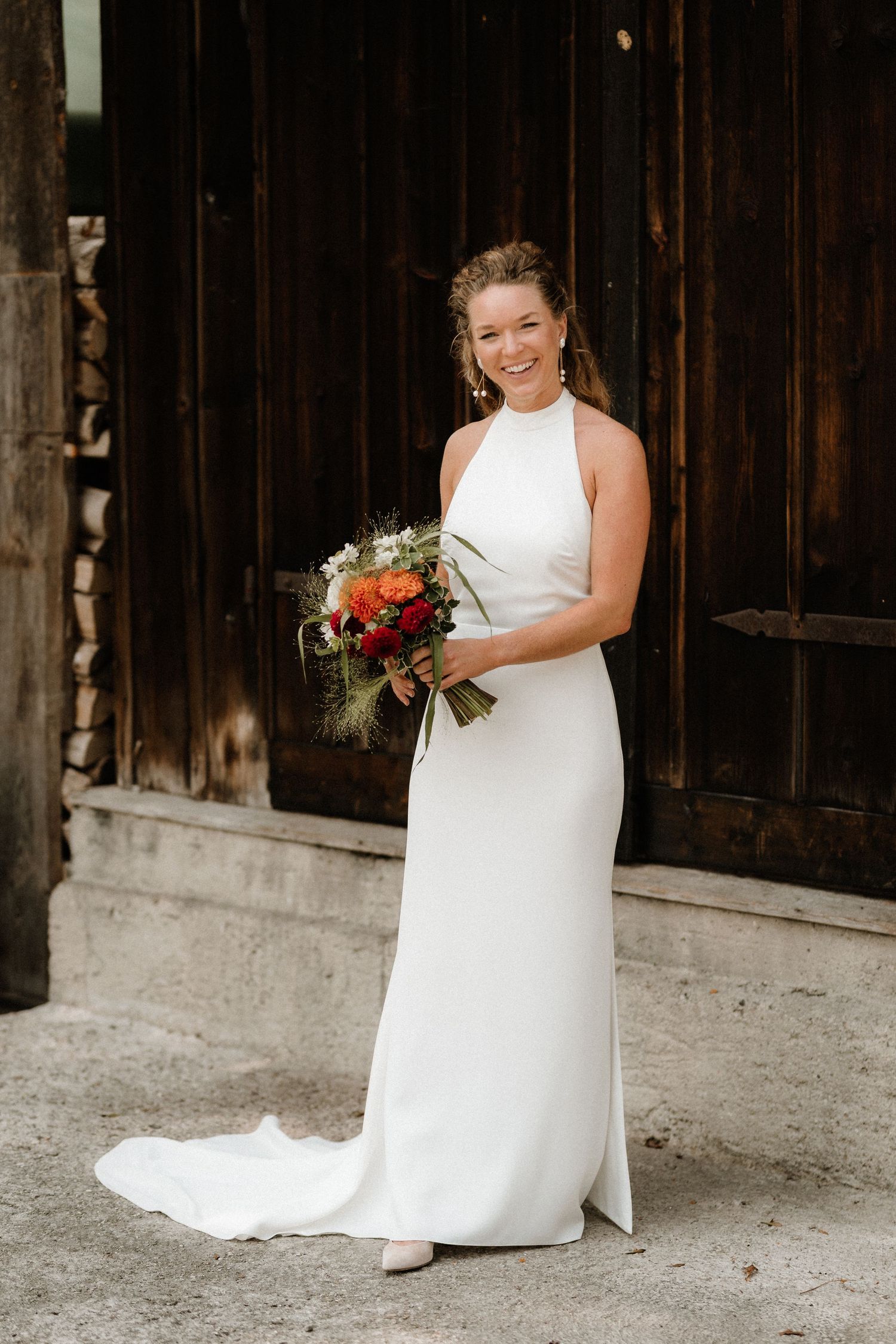A wedding photo session takes place in front of a rustic wooden barn.