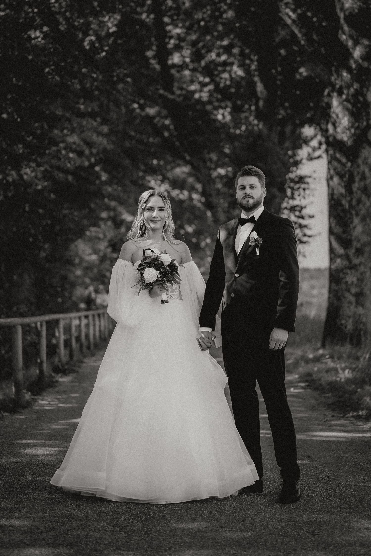 A romantic black and white wedding photo series showing a couple walking together in a tree-lined path.