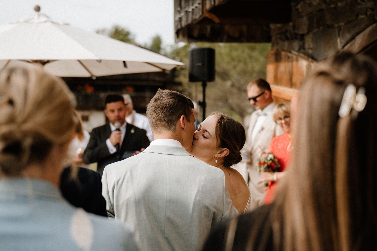 Guests gather under white umbrellas at an elegant outdoor wedding venue.