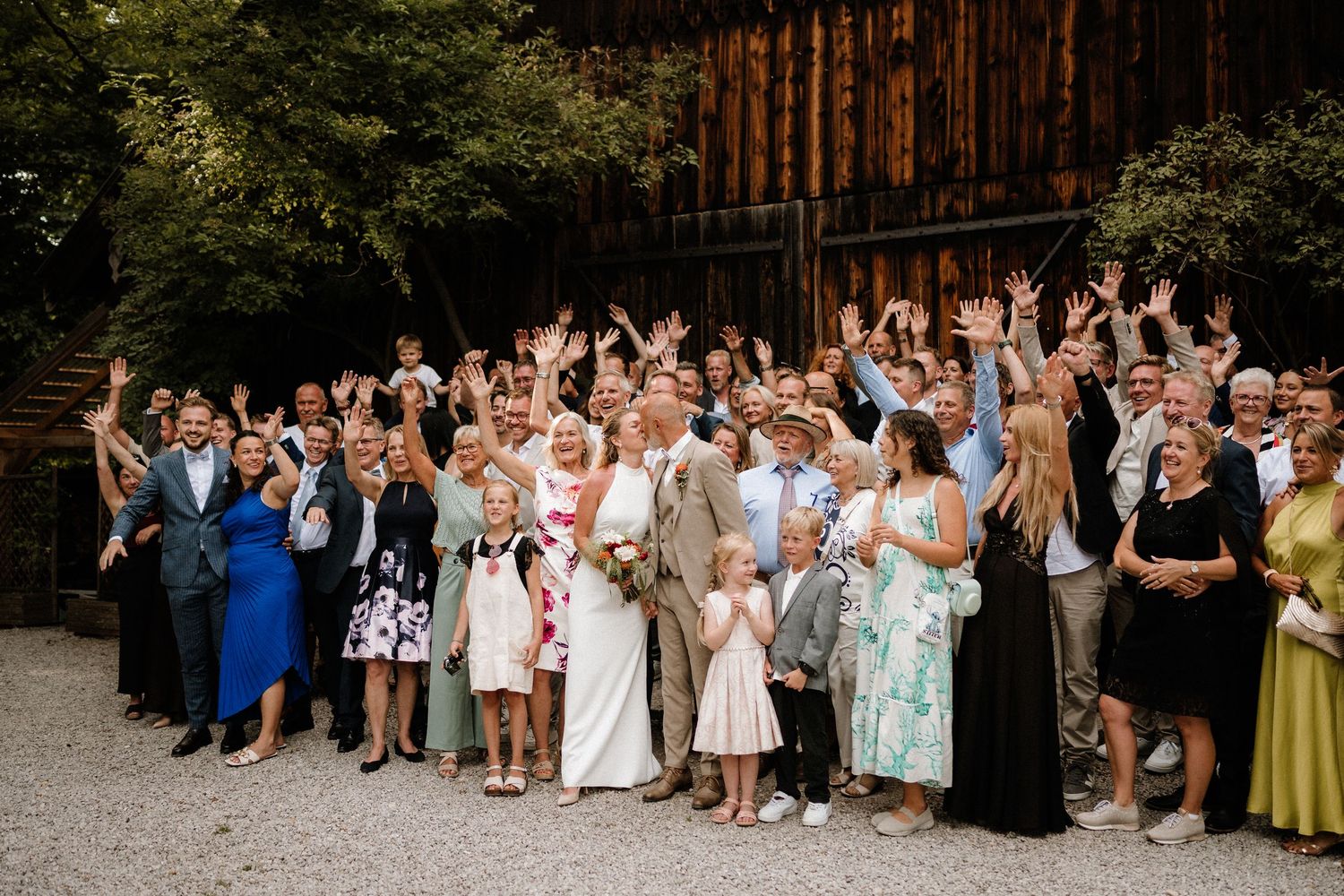 Large group of wedding guests gathered outside a rustic barn venue.