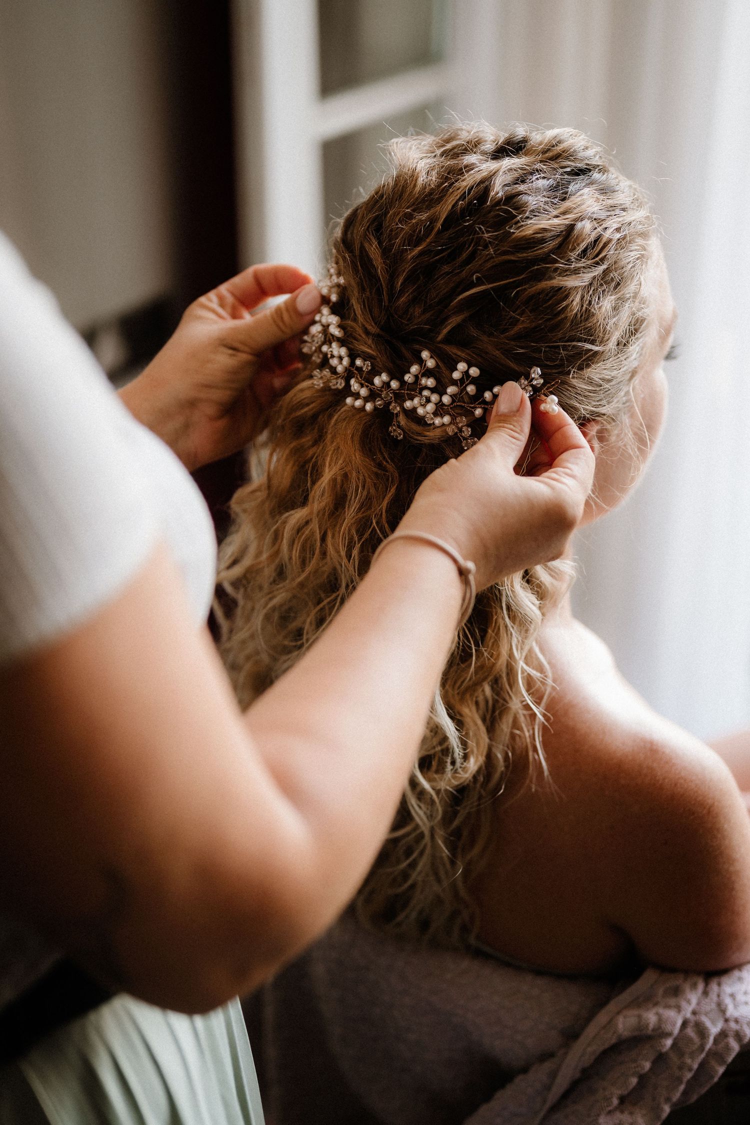 Close-up shot of hands arranging bridal hair accessories and styling.