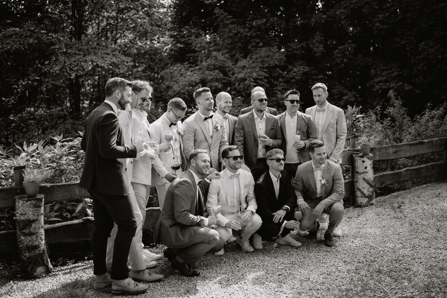 Wedding party and guests lined up for formal group photos on grassy grounds.
