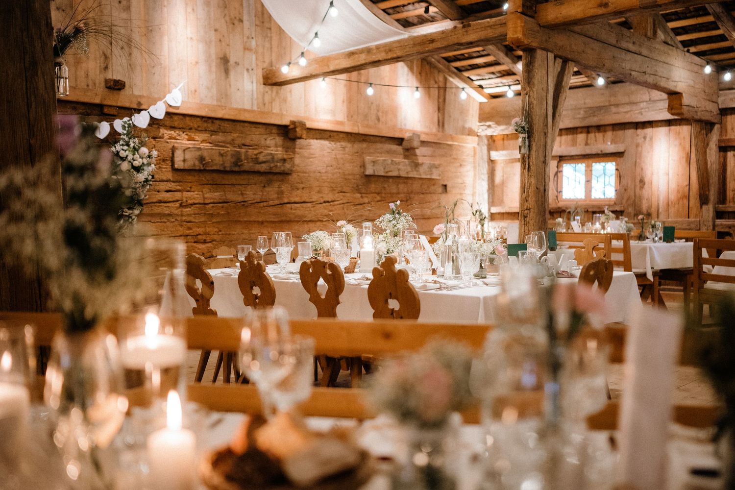 Rustic wooden reception venue with elegant table settings and candlelight.