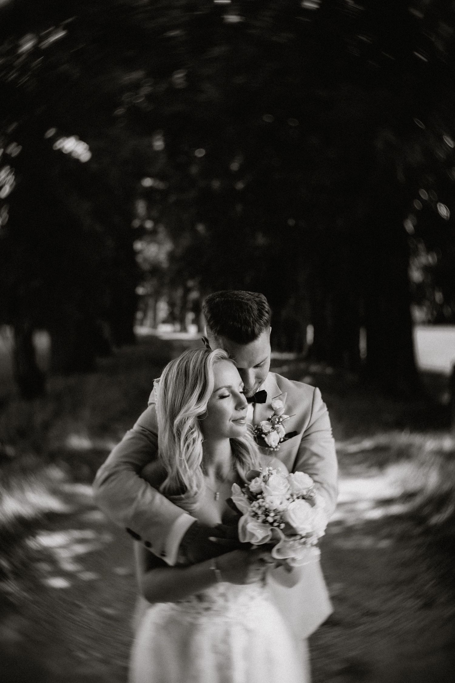 Intimate black and white wedding portraits captured in dappled forest light.