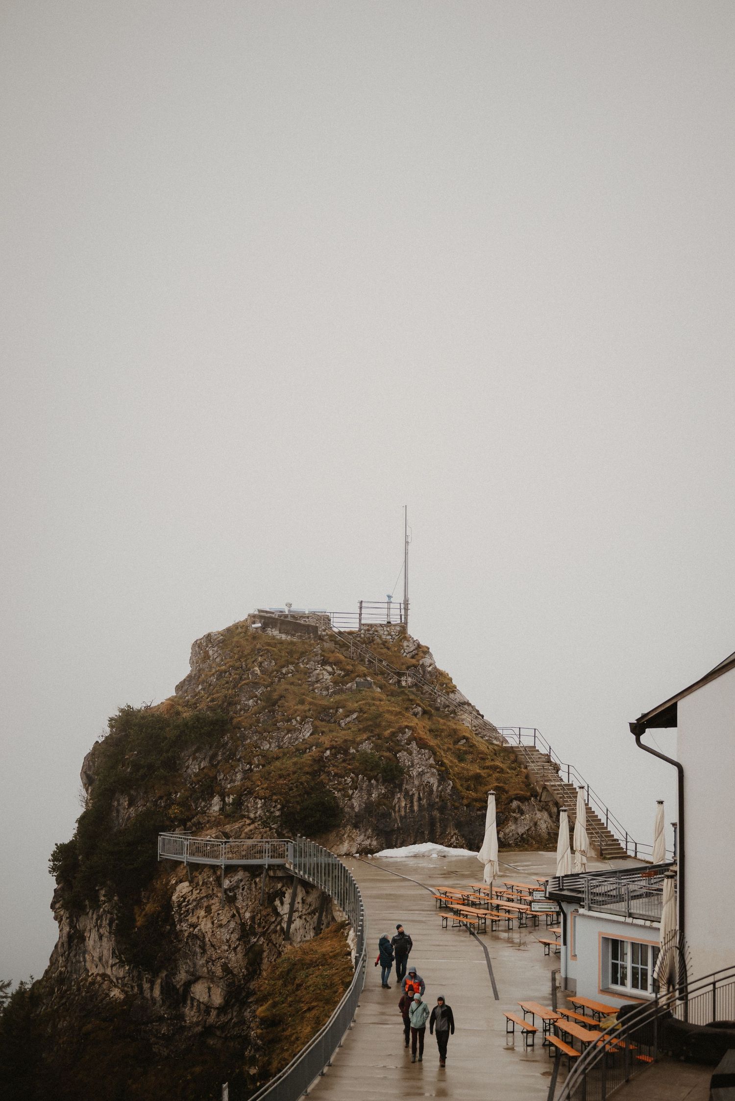Foggy mountain viewpoint with wooden walkway leading to rocky peak overlook.