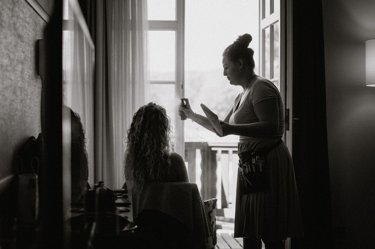 Black and white image of people getting ready by a window.