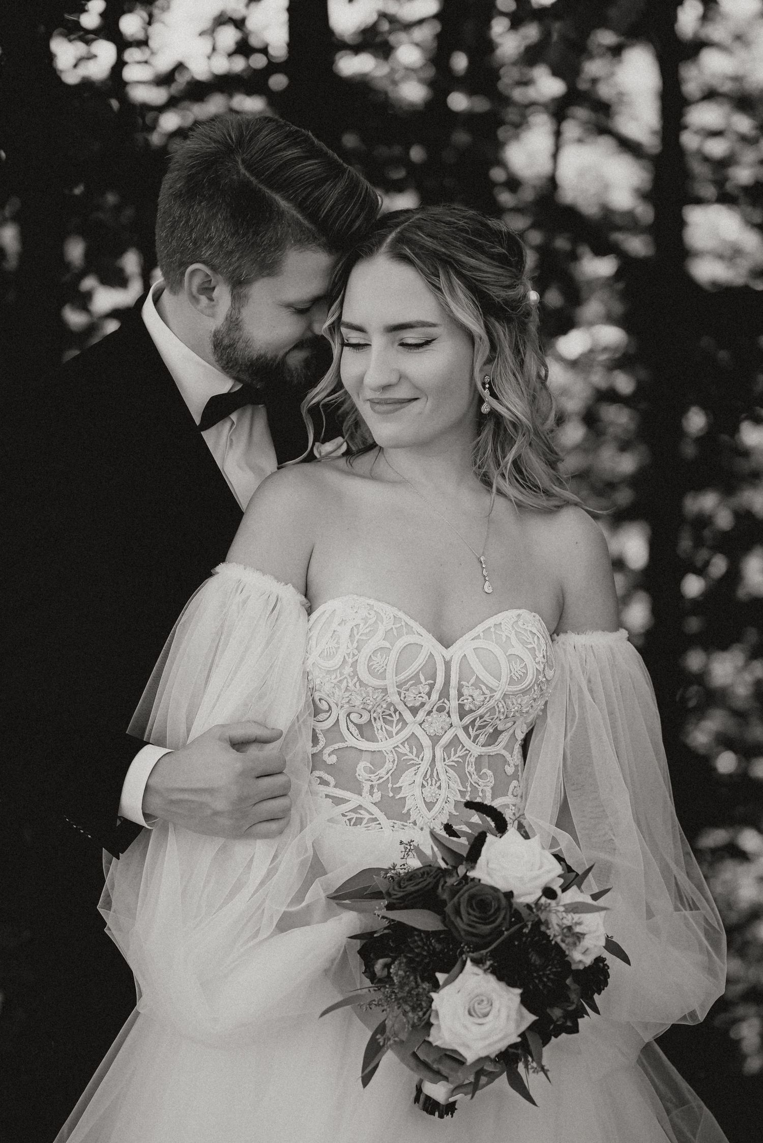 An intimate black and white portrait of newlyweds sharing a tender moment.