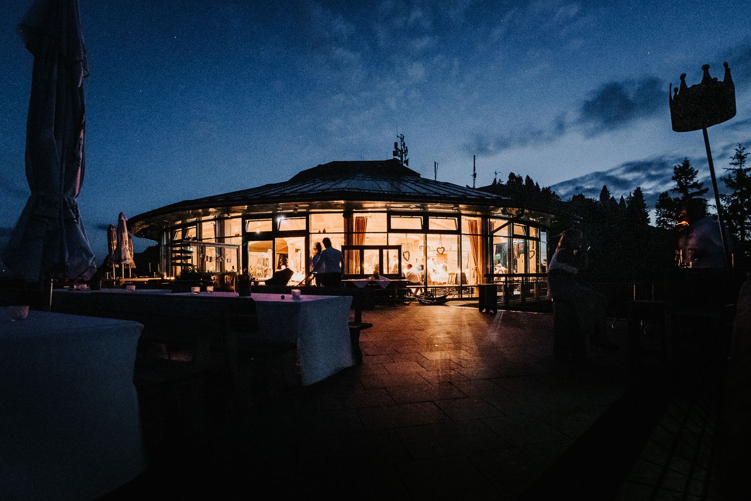 Illuminated modern building with large windows glows warmly against dark evening sky at twilight.