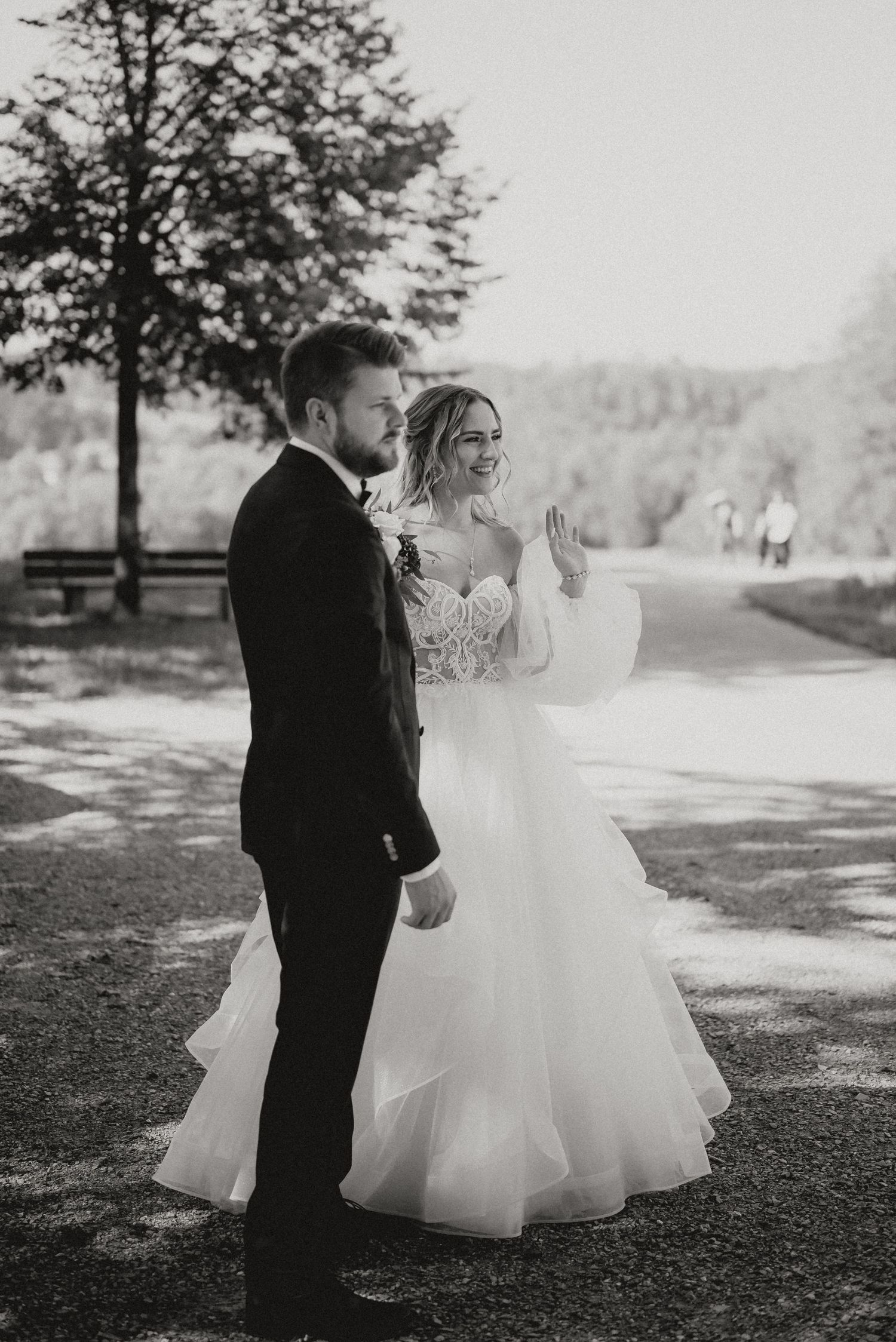 A black and white wedding photo capturing a candid moment between newlyweds outdoors.