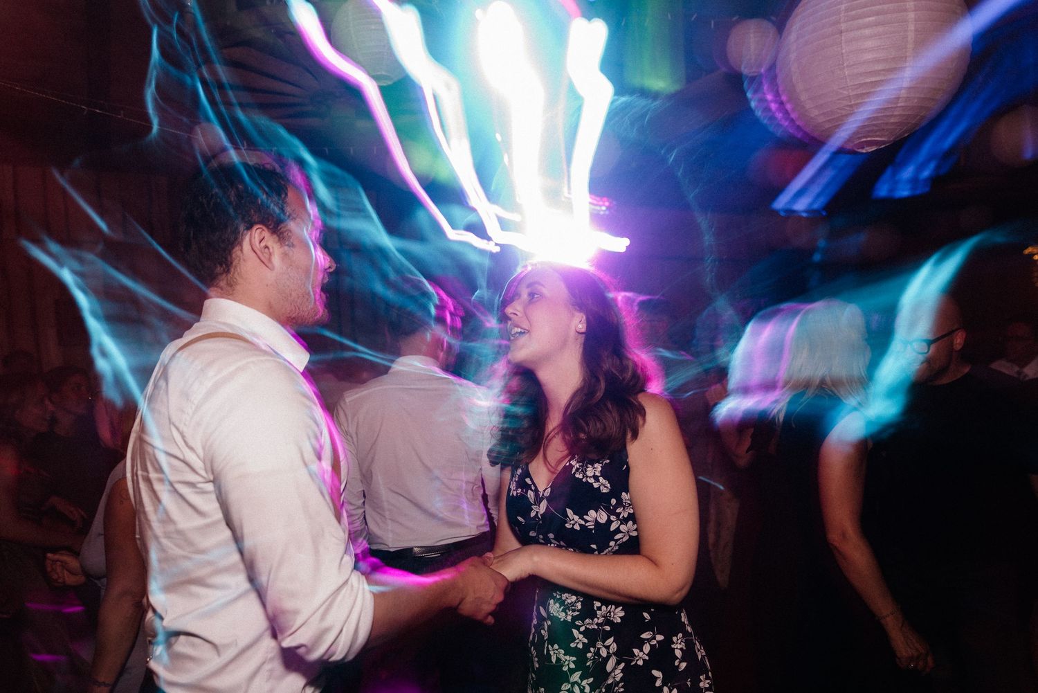 Dance floor filled with party guests under dramatic blue and white lighting.