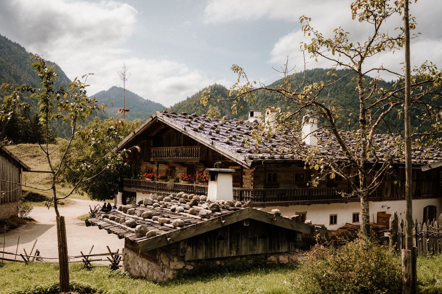 Traditional alpine buildings nestled in a mountainous landscape under cloudy skies.