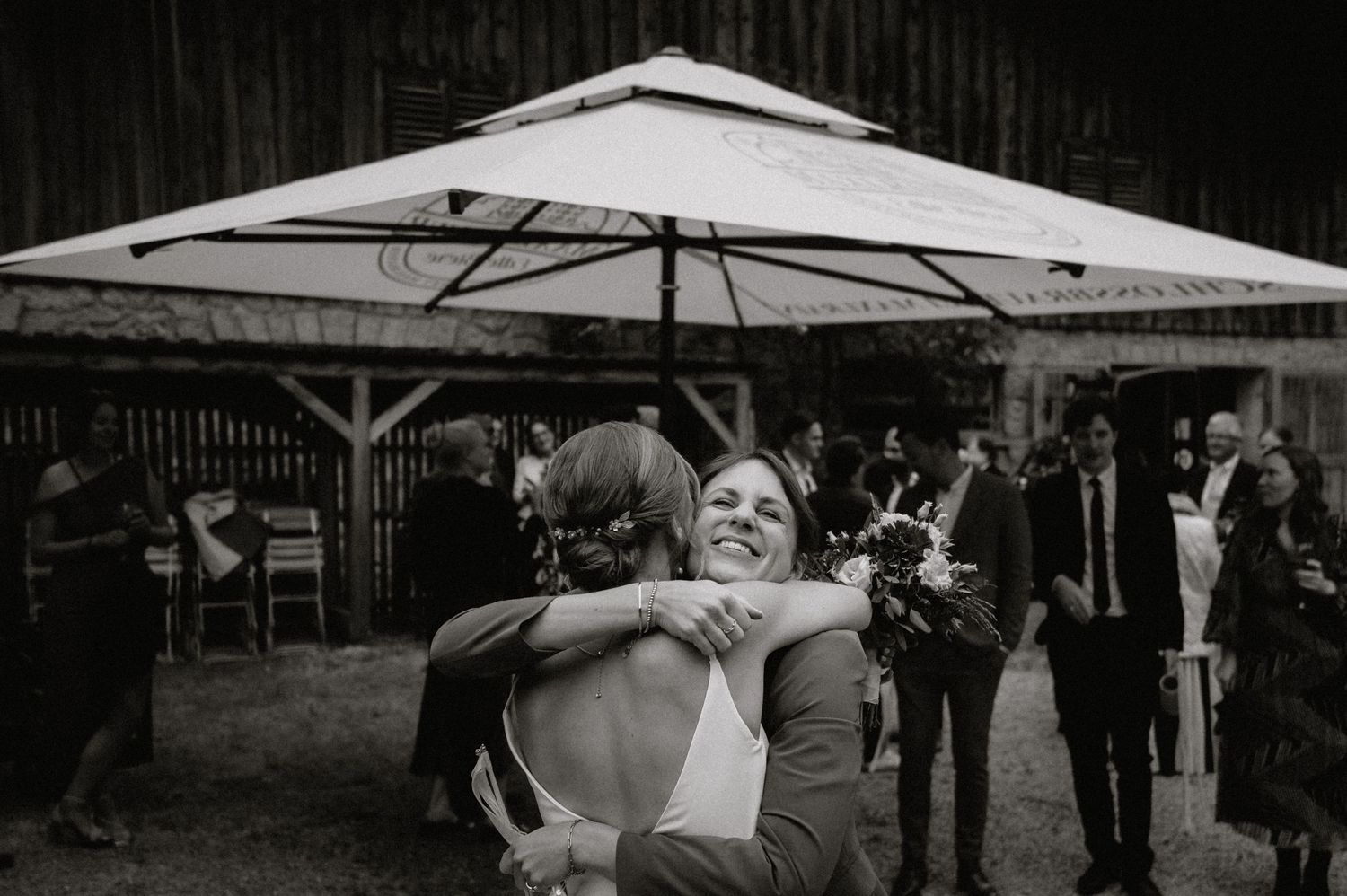 Guests watch as couple performs traditional wedding log sawing ritual at rustic outdoor venue.