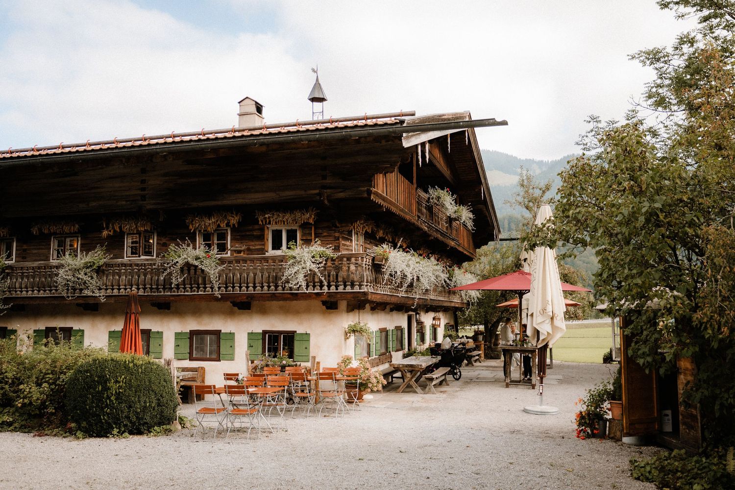Traditional Bavarian chalet-style building with wooden balconies and outdoor seating area.