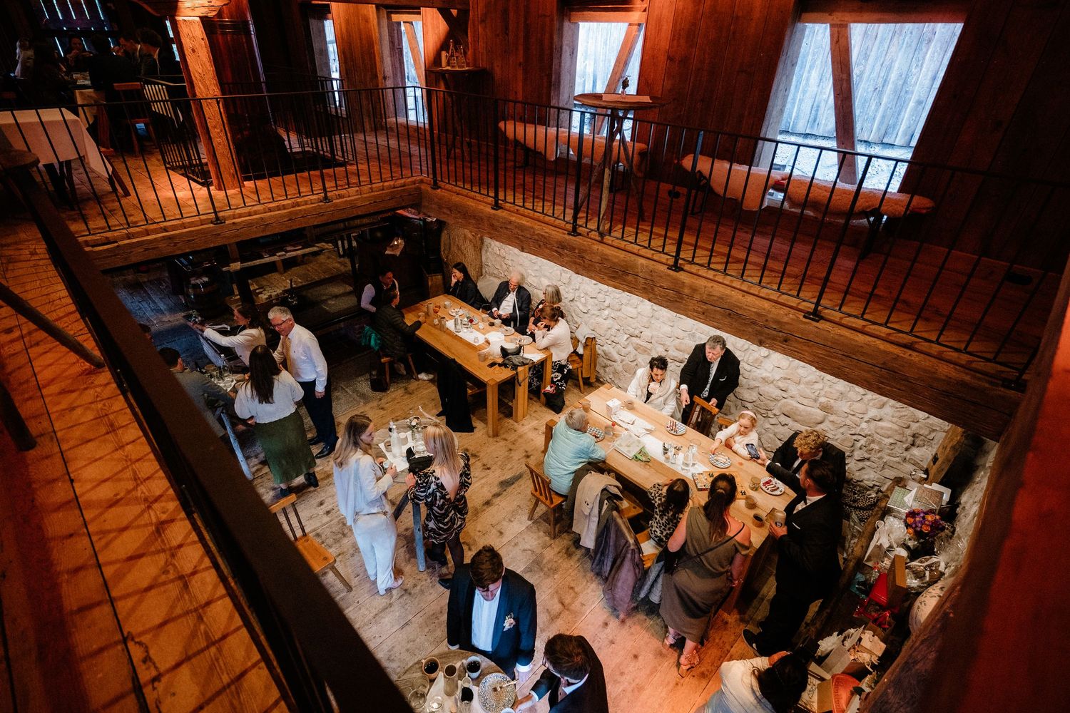 Guests mingling in a rustic barn venue with wooden beams and ambient lighting.
