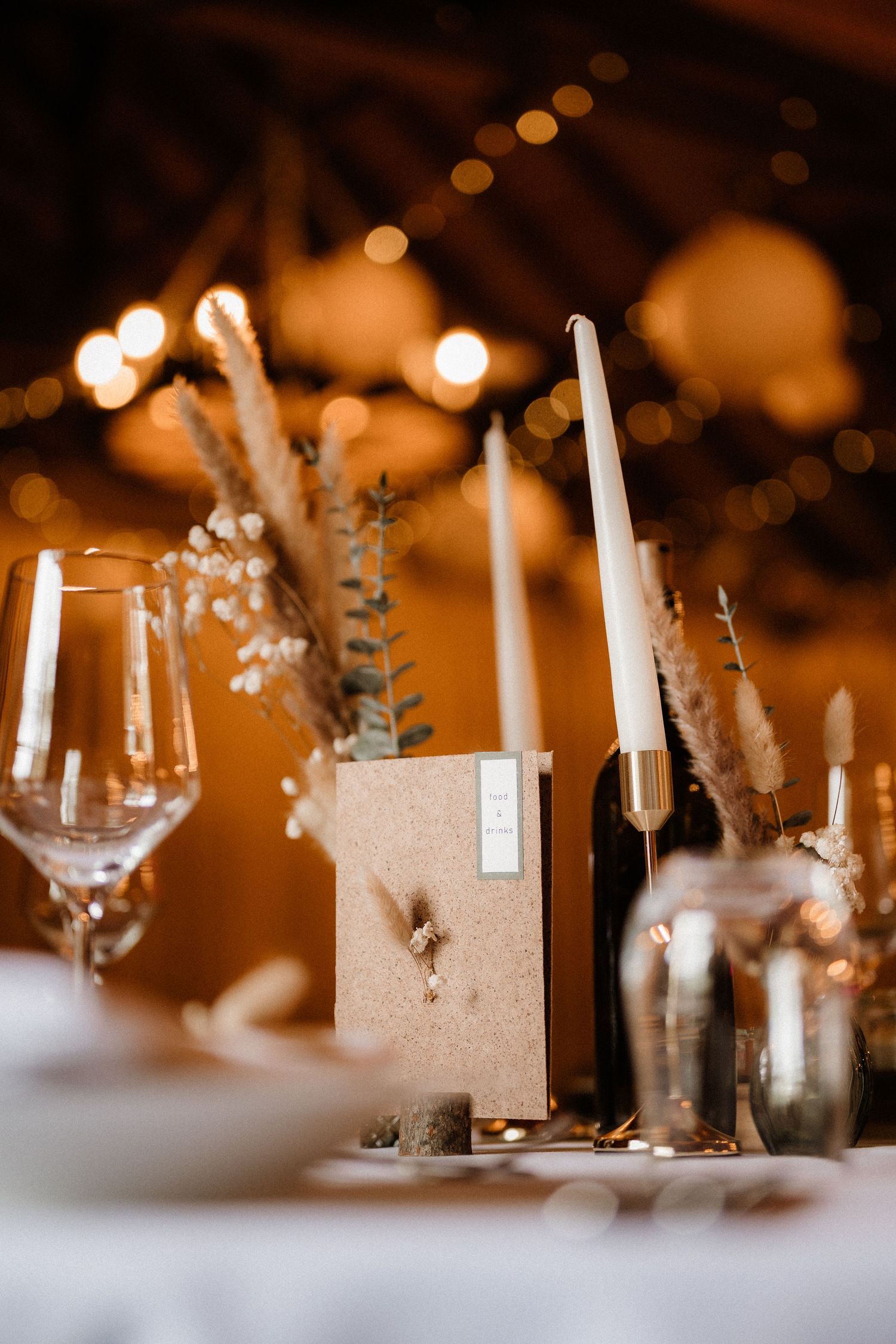 Elegant wedding table settings with white candles and floral centerpieces in warm lighting.