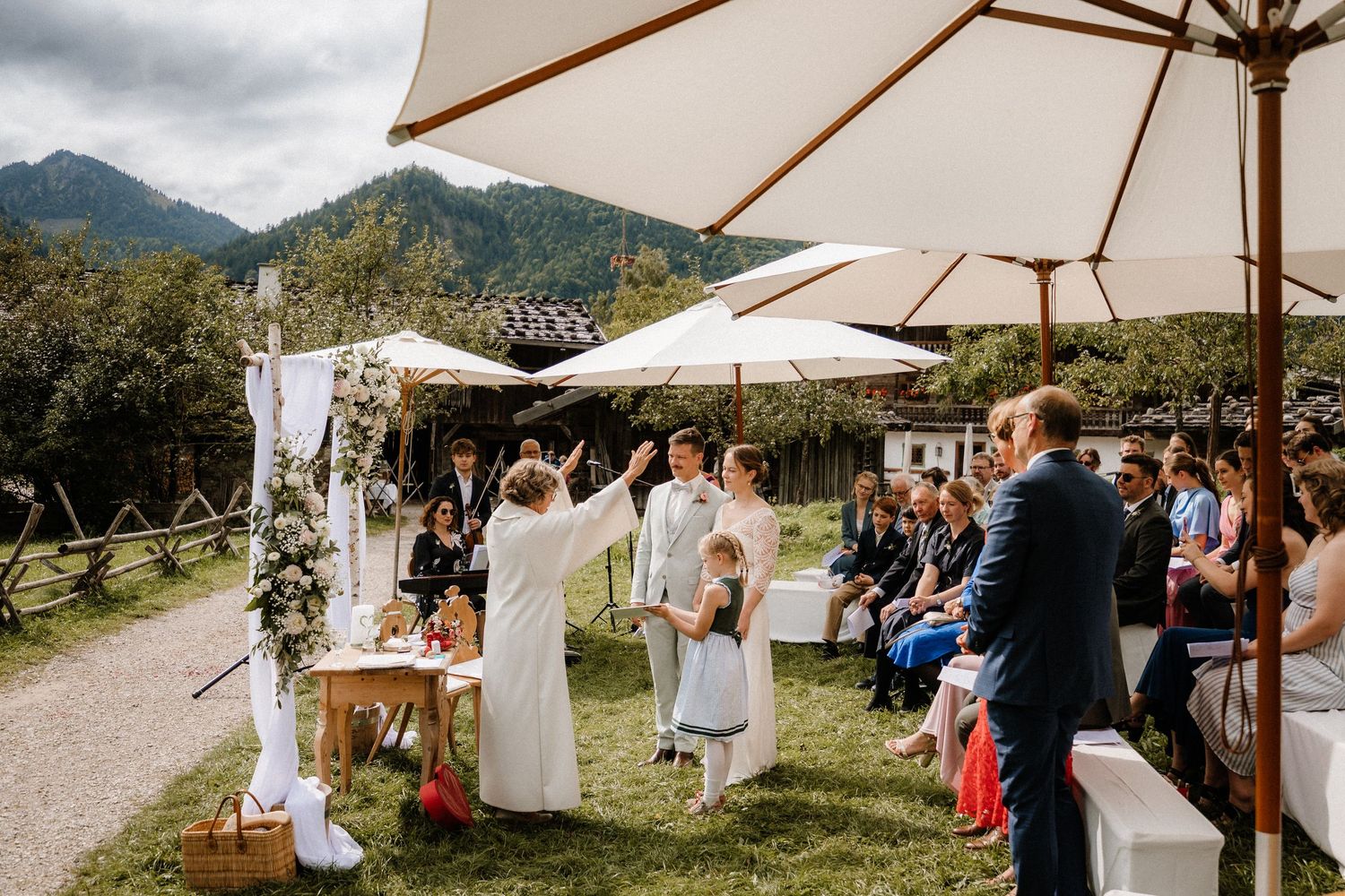 Scenic mountain wedding ceremony setup with white umbrellas and mountain views.