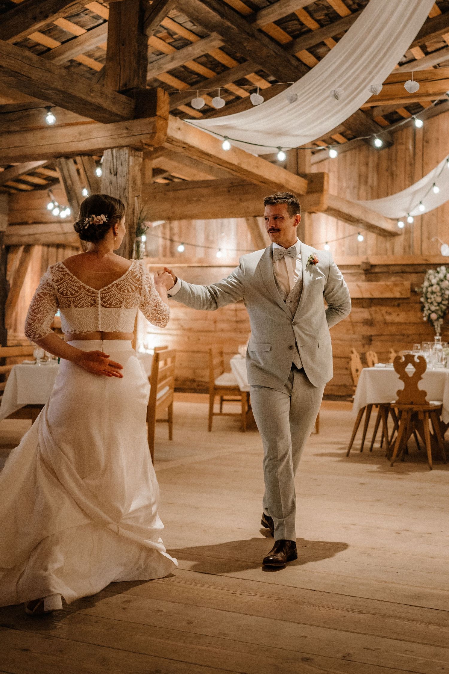 First dance in a wooden barn venue with draped white fabric decor.